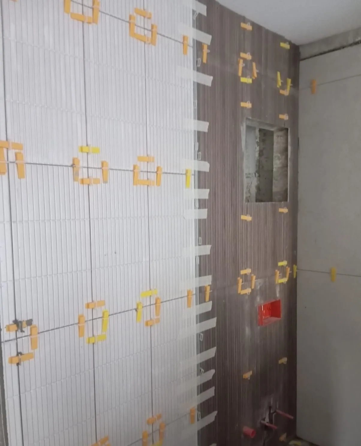 Duvar fayansları tesviye klipsleriyle döşenirken, ahşap desenli vurgu duvarı